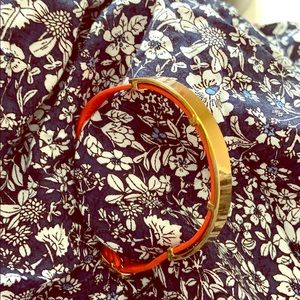 Red leather bracelet with gold band.